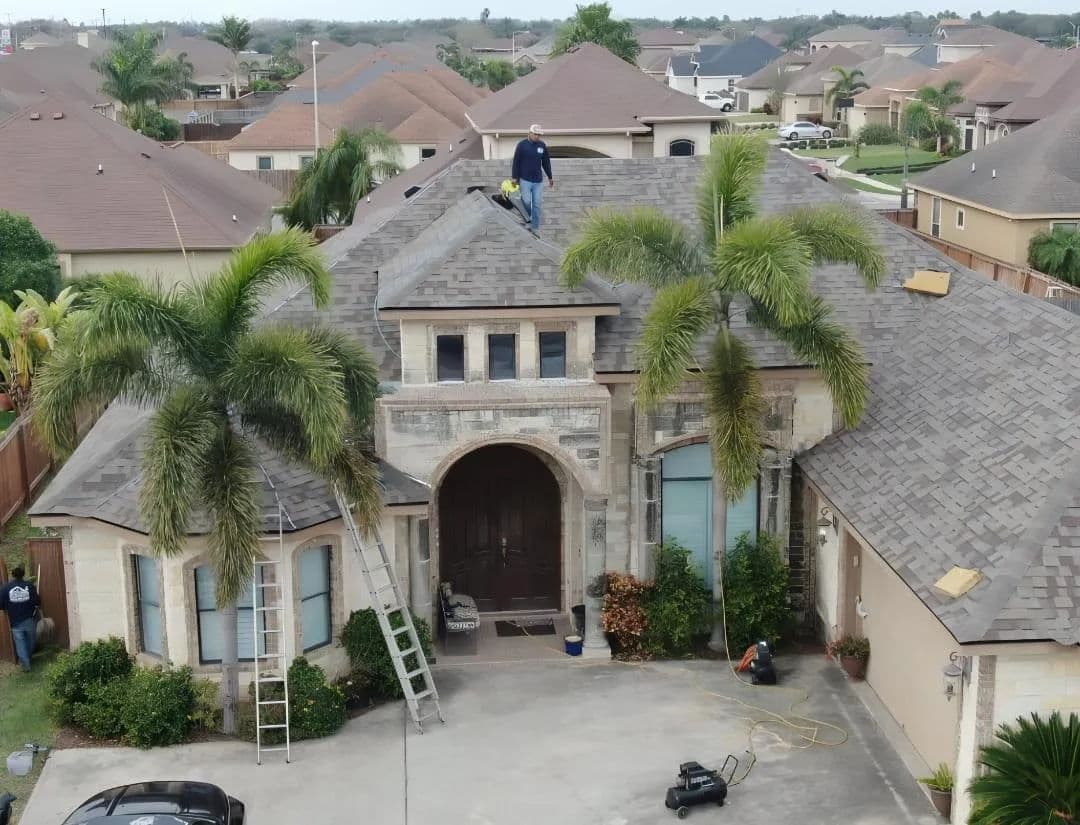 Roofing contractors working on a home in a suburban neighborhood with palm trees.