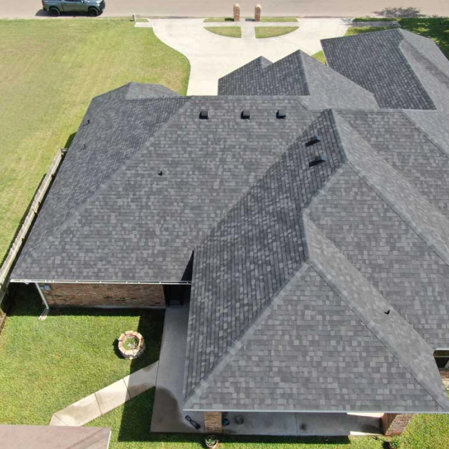 light brown house with a grey roofing and a big patio around