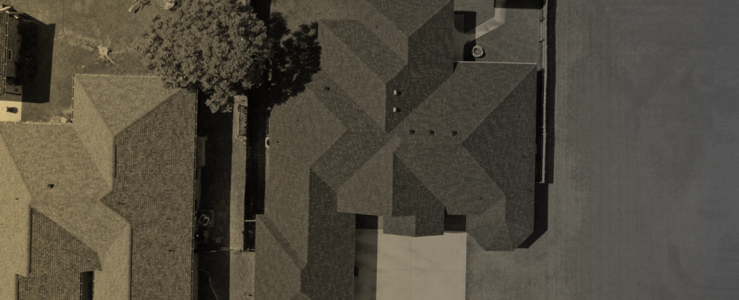 light brown house with grey roofing and a tree at the left