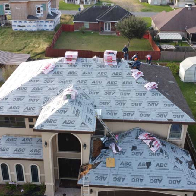 roof replacement of a beige house with some materials and some contractors working on it